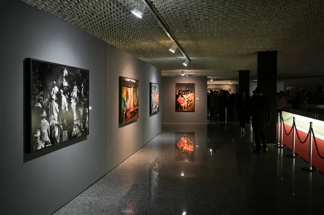 Corredor da exposição com fotografias iluminadas nas paredes.