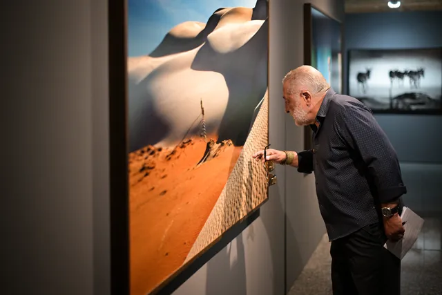 Araquém Alcântara ao lado de uma fotografia de dunas, na abertura da exposição.