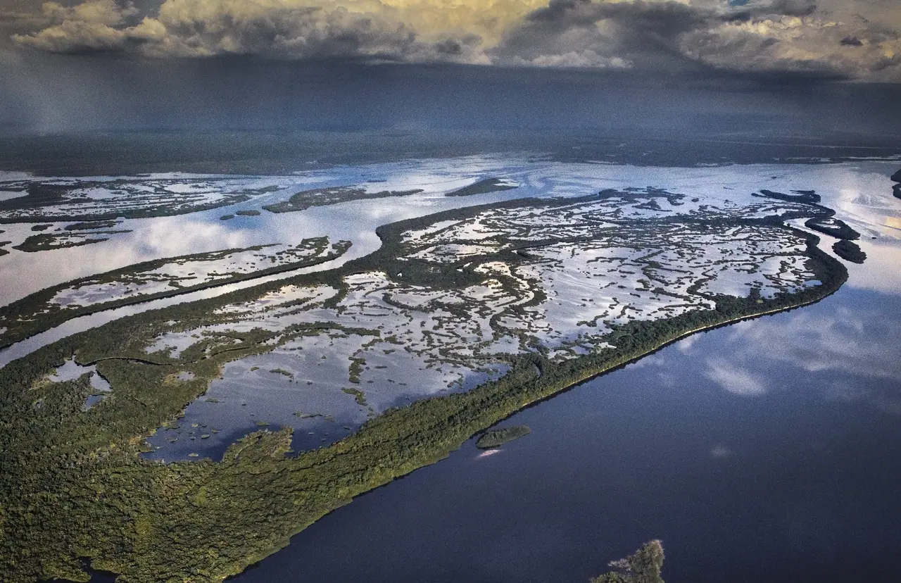 Aerial view of river channels and flooded islands under a stormy sky.