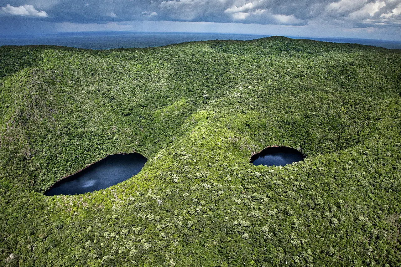 Vista aérea de floresta densa com duas lagoas escuras entre os morros